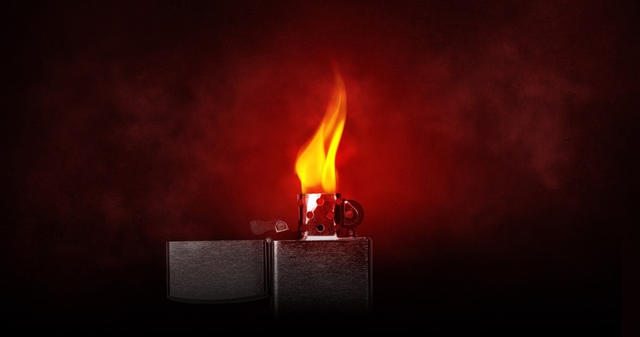 Brennendes Zippo vor rot/schwarzem Hintergrund